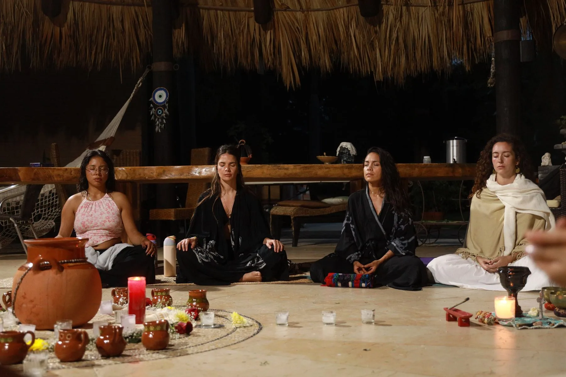 Women seated in a ritual circle around candles and clay vessels